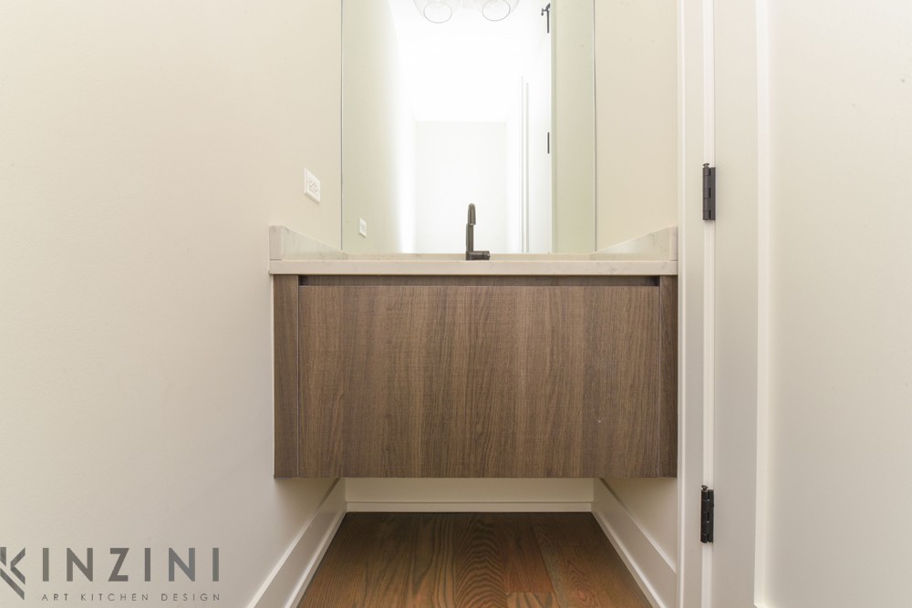 A modern bathroom featuring a wooden floating vanity with a sleek black faucet. The walls are a light color, the floor is wooden, and the room is illuminated by natural light. 